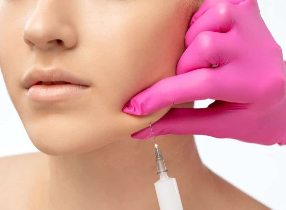 Clinician administering fat-dissolving injections to a patient's double chin area